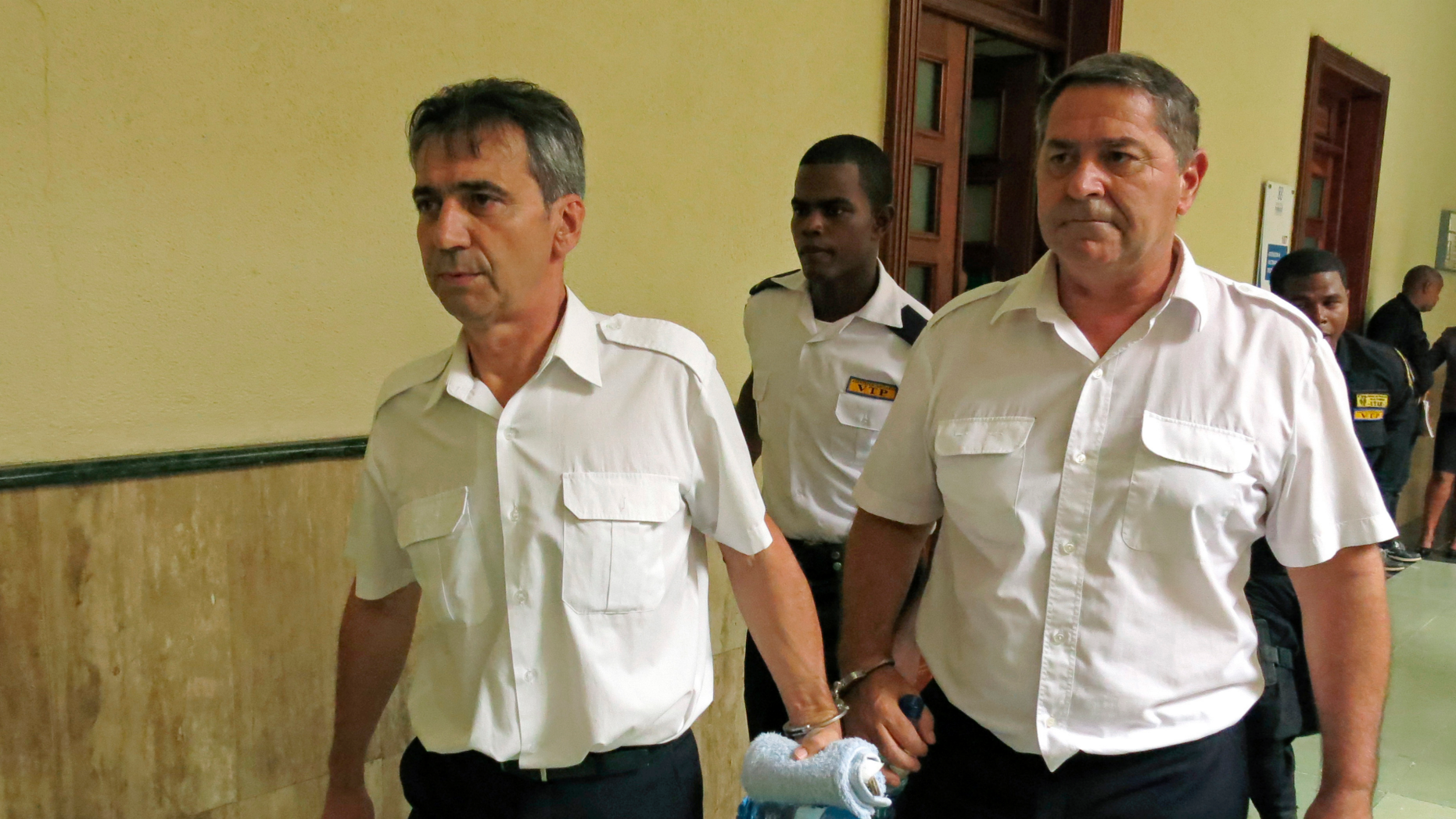 FILE - In this dossier of 17 June 2014, the French pilots Bruno Odos (left) and Pascal Jean Fauret, who were officially charged with drug trafficking, are escorted to a courtroom in Santo Domingo, Dominican Republic. In southern France, nine men are being tried for alleged cocaine trafficking between the Caribbean and Europe, including two pilots who fled the Dominican Republic to avoid 20-year jail sentences. (AP Photo / Ezequiel Abiu Lopez, File)
